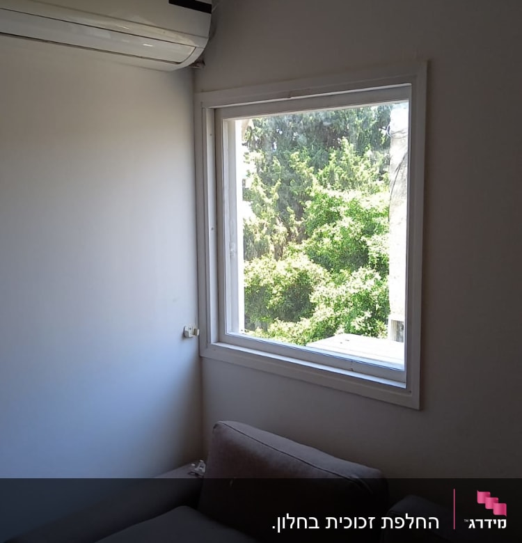 חלון זכוכית עם נוף עצים ירוקים בחוץ